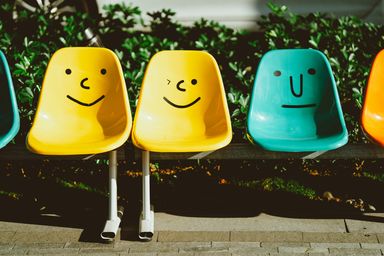 Cadeiras coloridas com expressões diferentes a representar a satisfação ou descontentamento dos condóminos numa gestão de condomínio